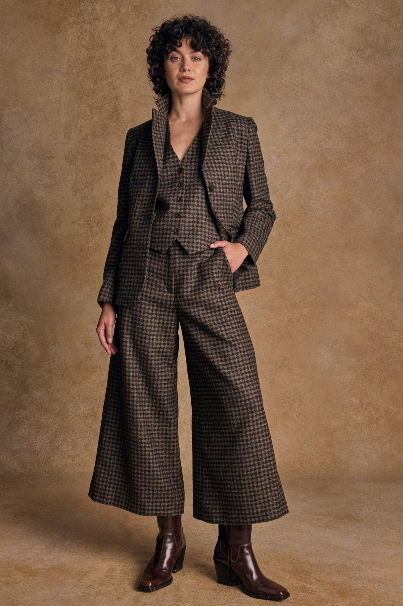 Woman wearing a brown tweed suit against a beige background