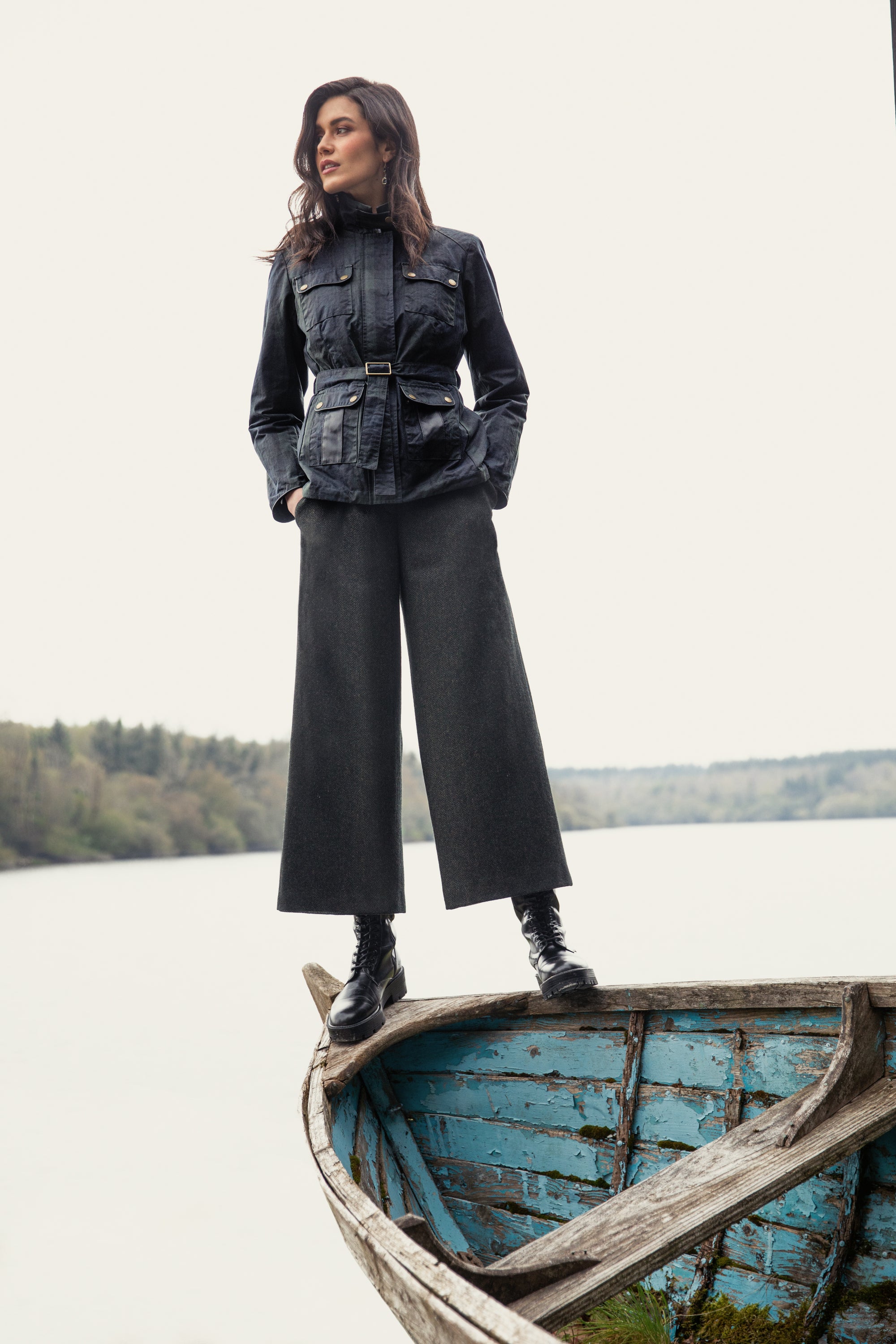 Woman standing on boat in Cara wax jacket black watch and Enya Tweed culottes