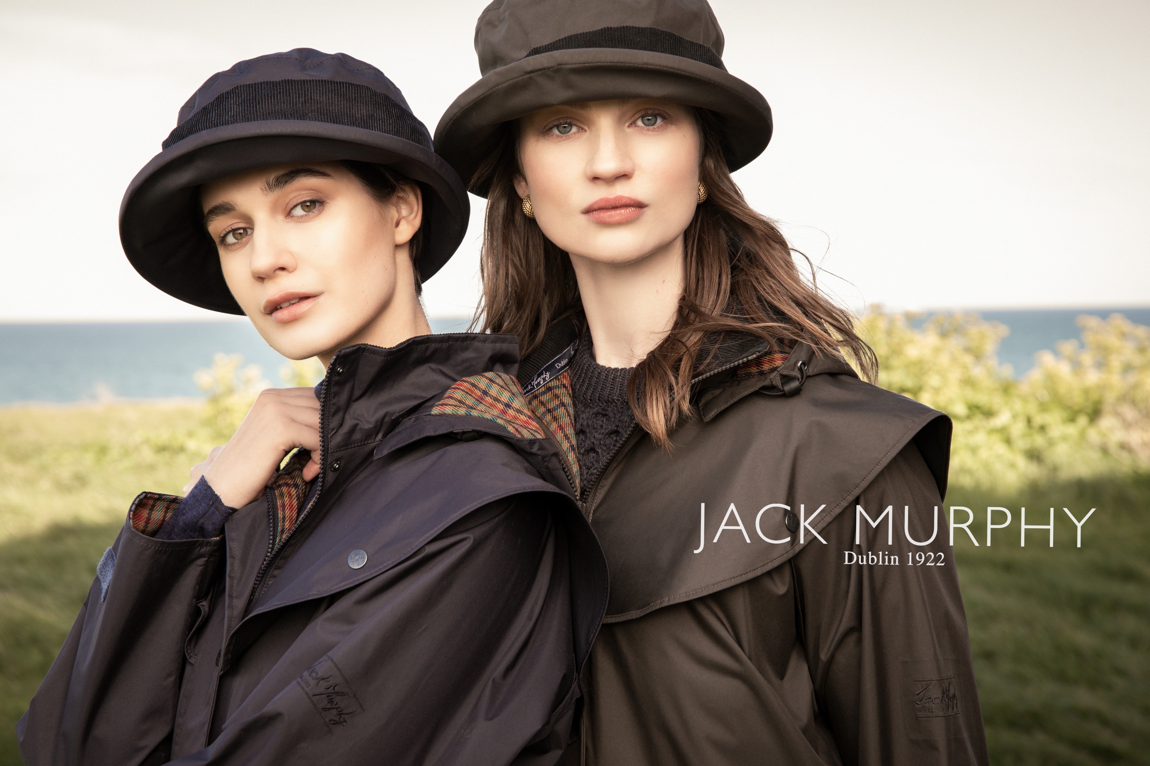 Two women in Malvern and cotswold waterproof jackets in Navy and olive and waterproof Malvern hat.