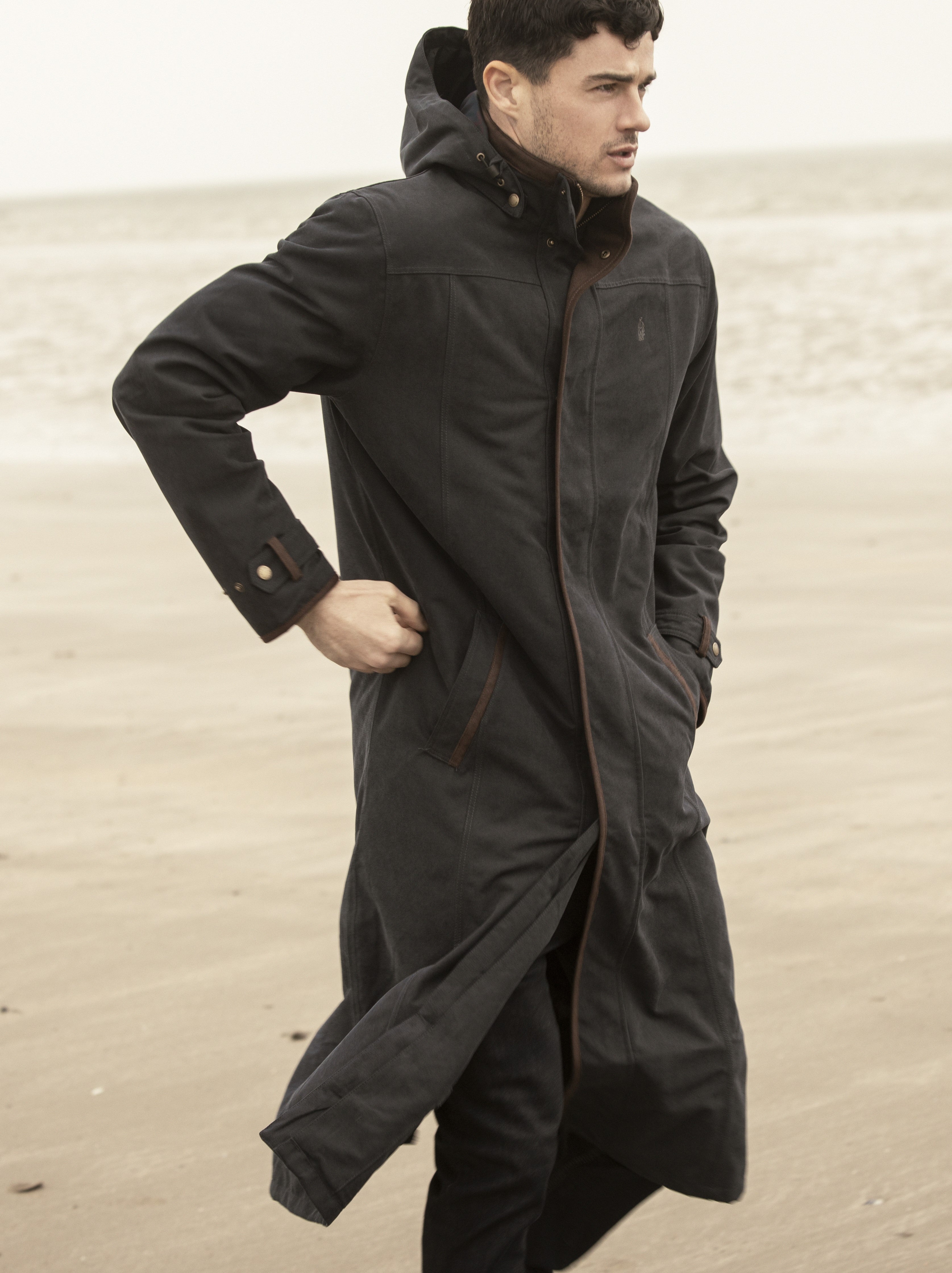 Man walking on Beach in waterproof long coat emmet in navy.