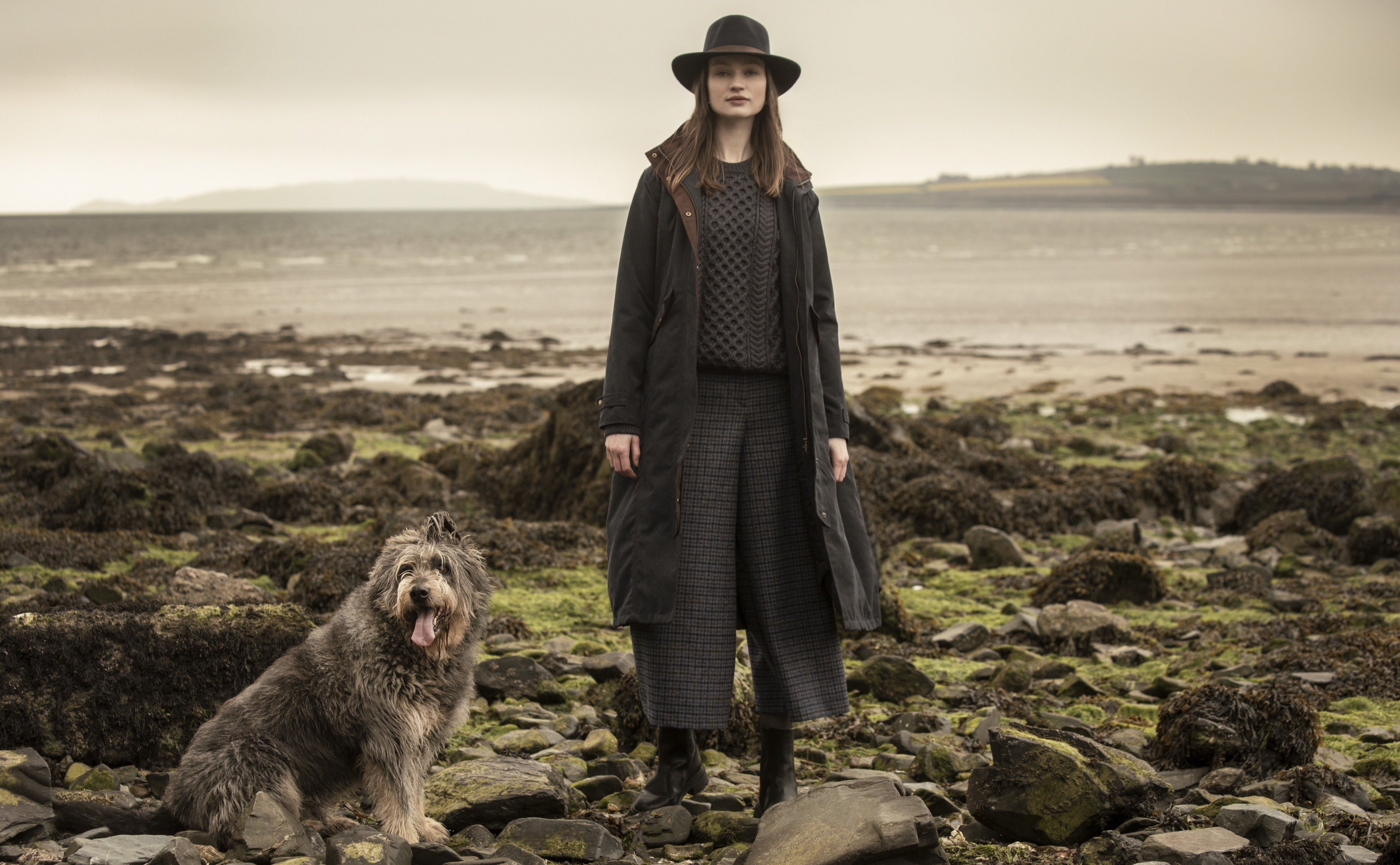 Woman and dog on beach in a waterproof erin jacket, enya tweed culottes And Boston felt hat in Brown.