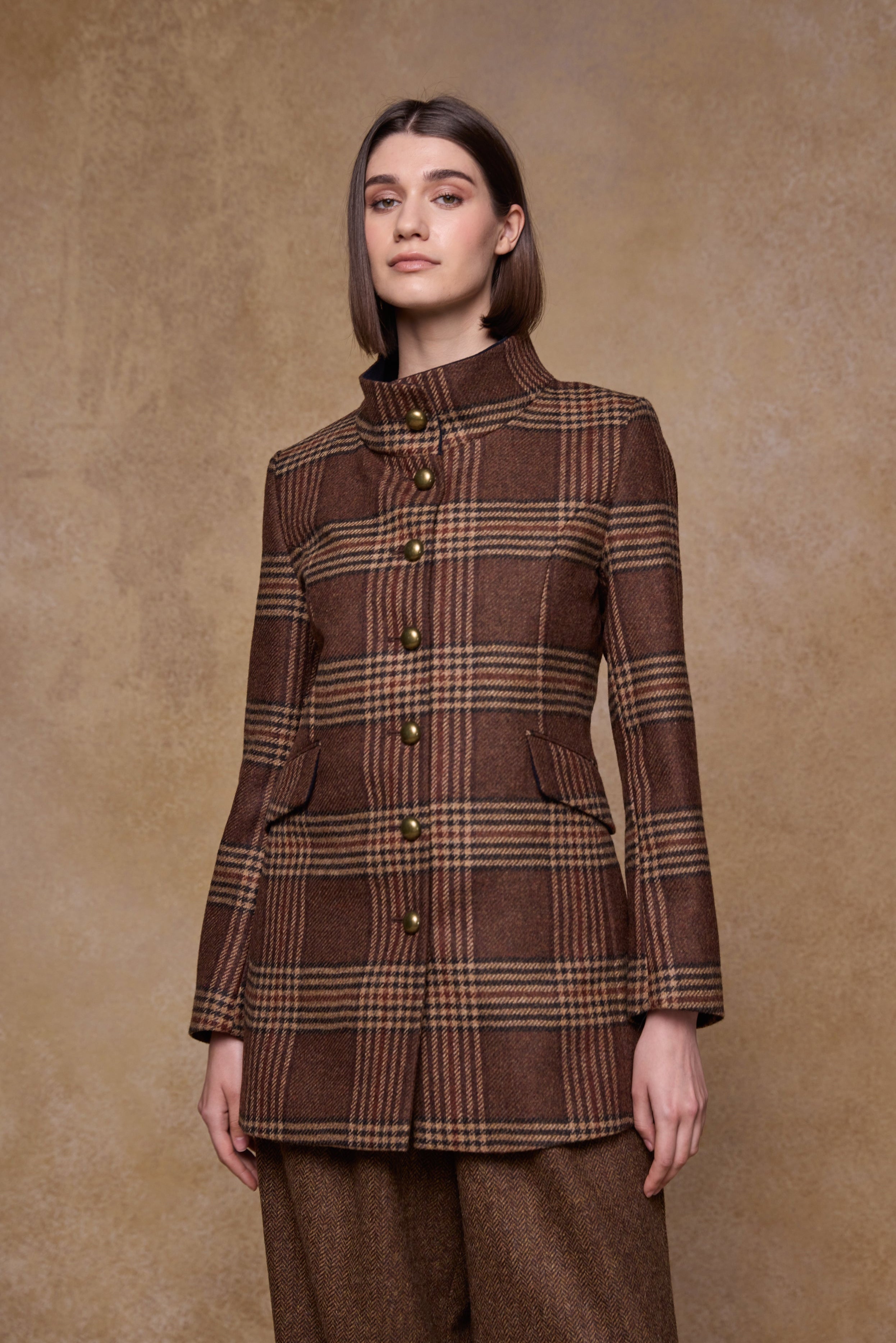 Woman wearing a brown tweed plaid coat against a beige background